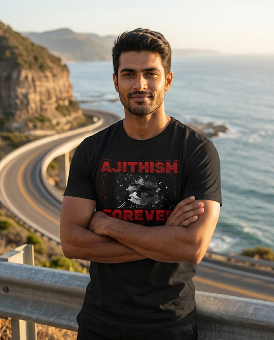 Young South Indian male wearing the AJITHISM FOREVER men's regular-fit t-shirt in black at a scenic coastal highway viewpoint.