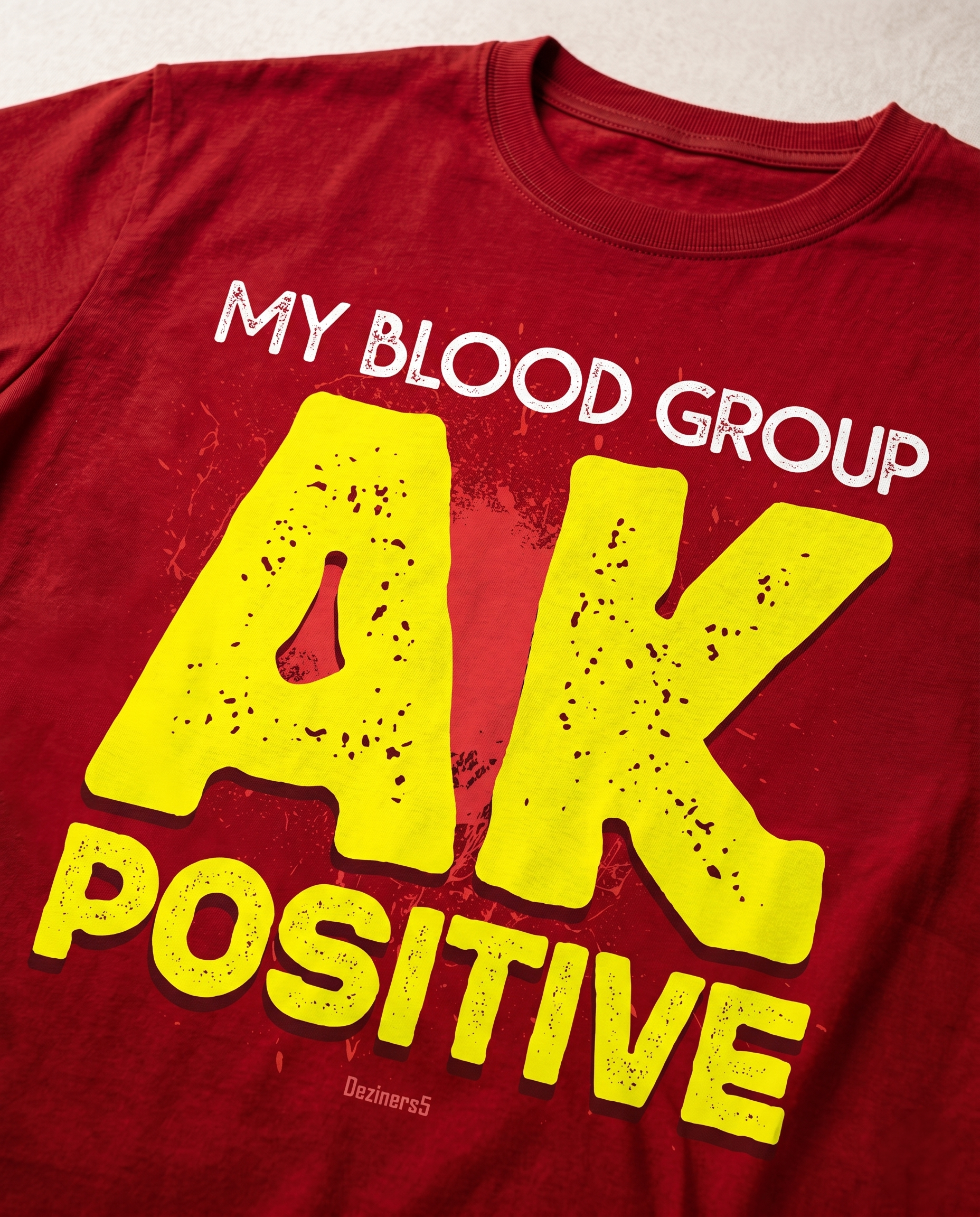 Detailed close-up of the AK POSITIVE front graphic print highlighting typography and premium print quality on a red men's regular-fit t-shirt.