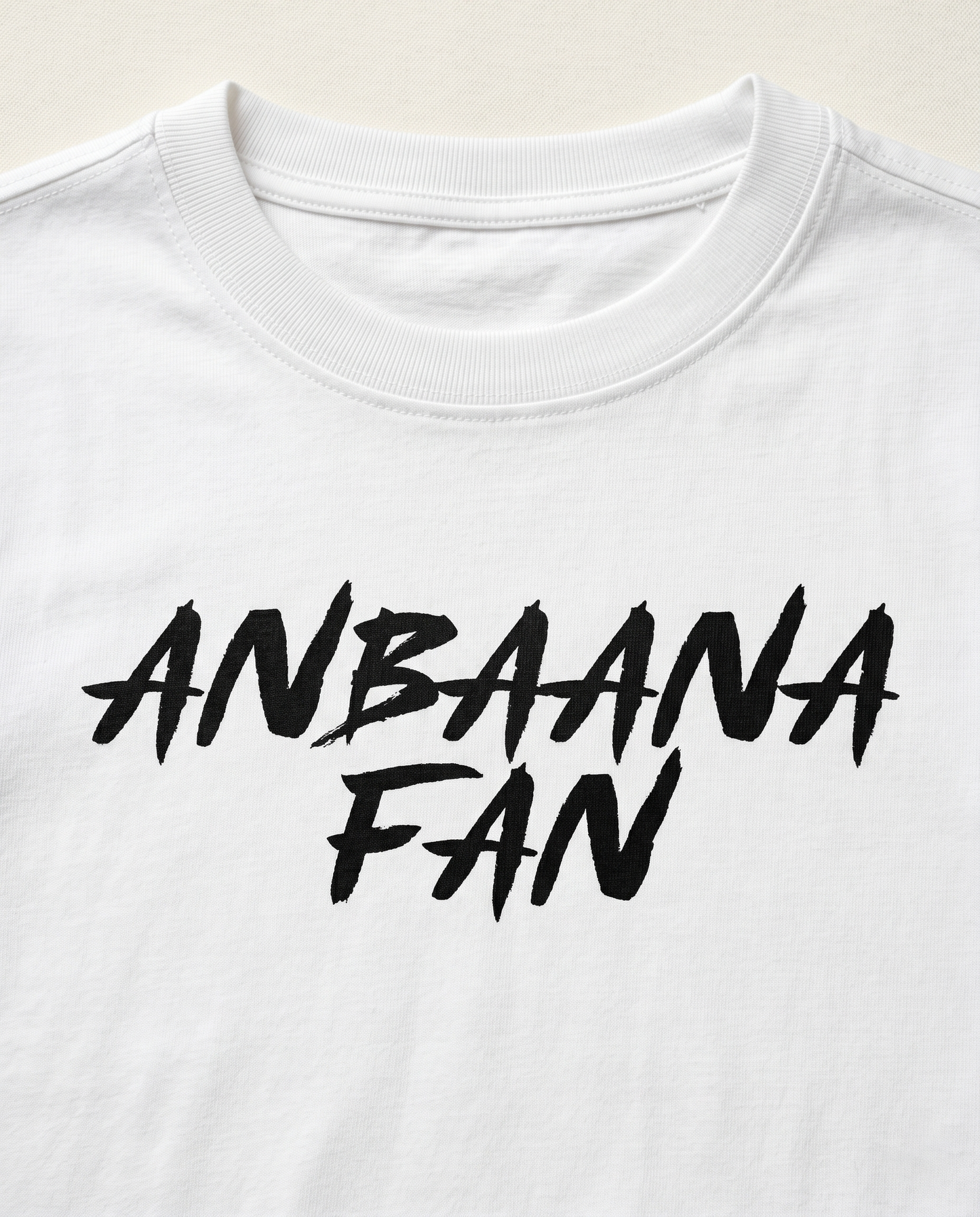 Close-up view of the ANBAANA FAN graphic print highlighting typography details and premium print quality on a white men's regular-fit t-shirt.