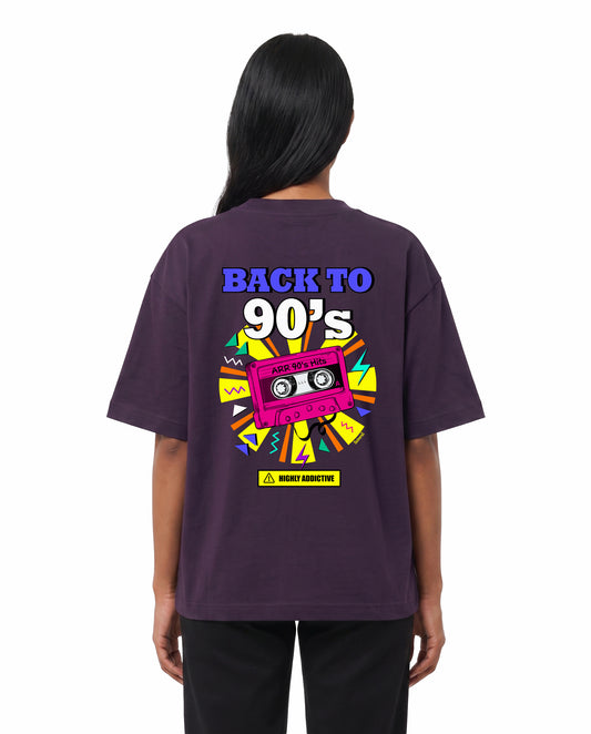 Back view of female model wearing ARR 90S HITS - Unisex Oversized Graphic T-Shirt in purple in a studio setting.