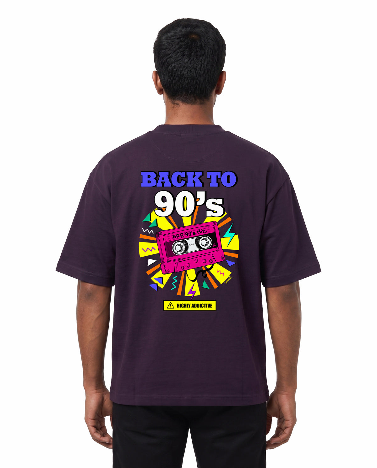Back view of male model wearing ARR 90S HITS - Unisex Oversized Graphic T-Shirt in purple in a studio setting.