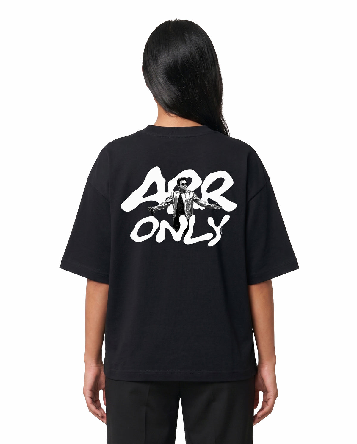 Back view of female model wearing ARR TRIBUTE - Unisex Oversized Graphic T-Shirt in black in a studio setting.