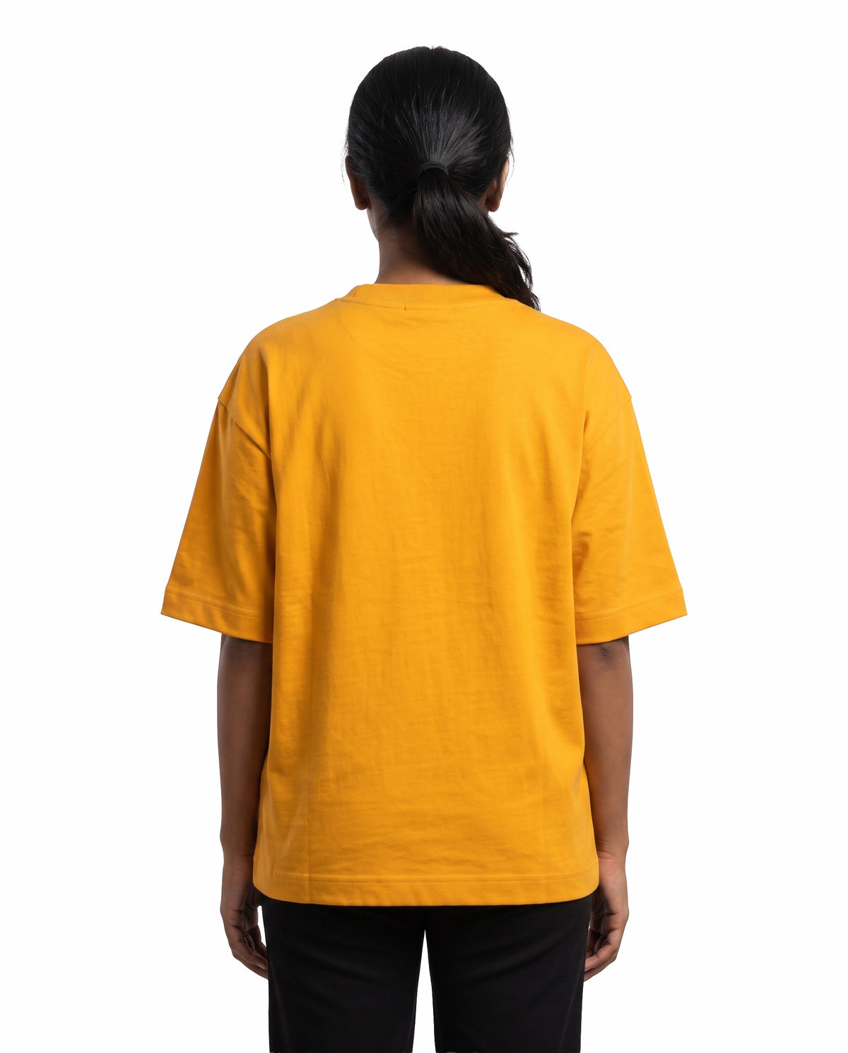 Back view of female model wearing ARR VIBES - Unisex Oversized Graphic T-Shirt in golden yellow in a studio setting.
