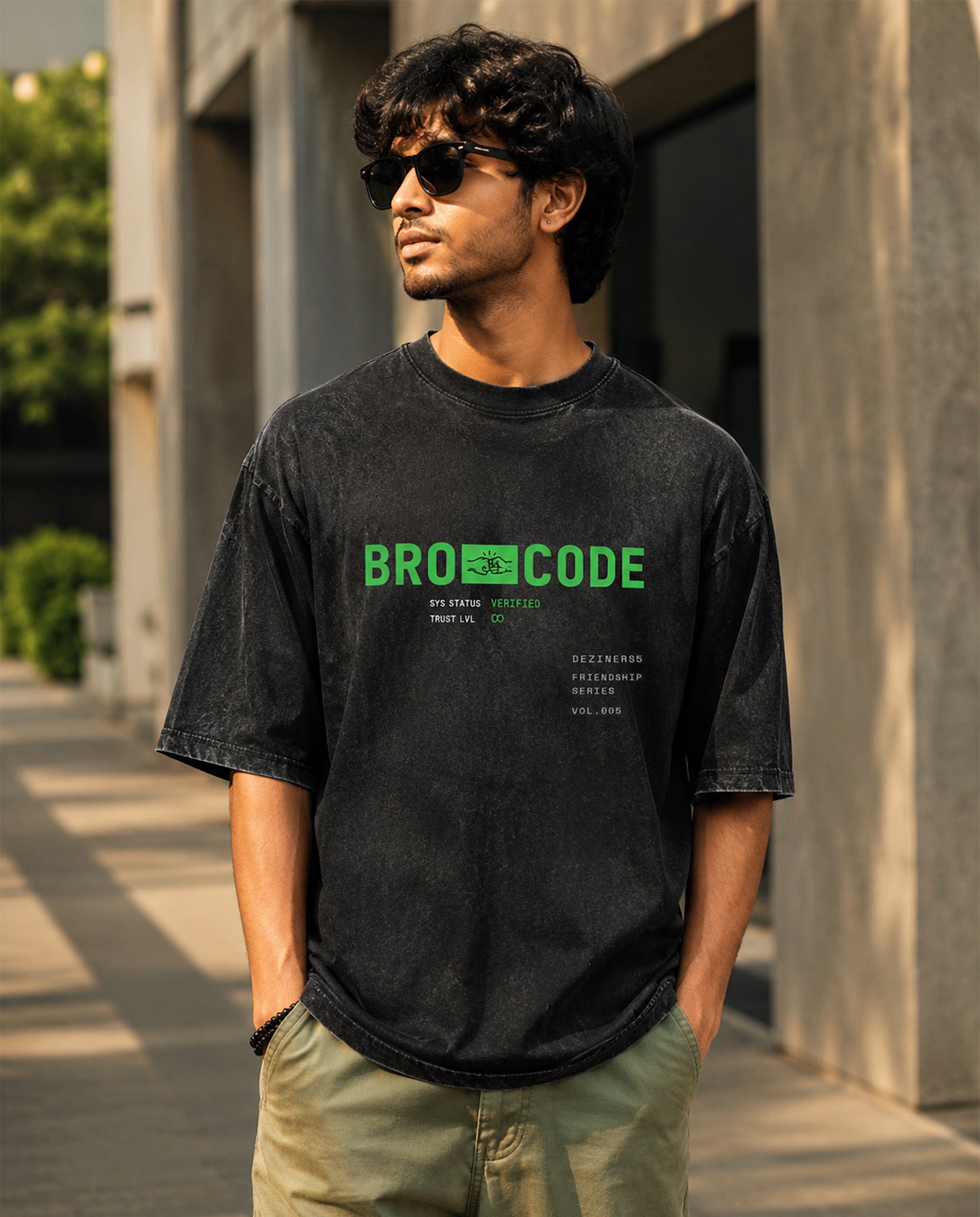 Lifestyle image of male model wearing BRO CODE unisex acid washed oversized graphic t-shirt in black in an urban setting.