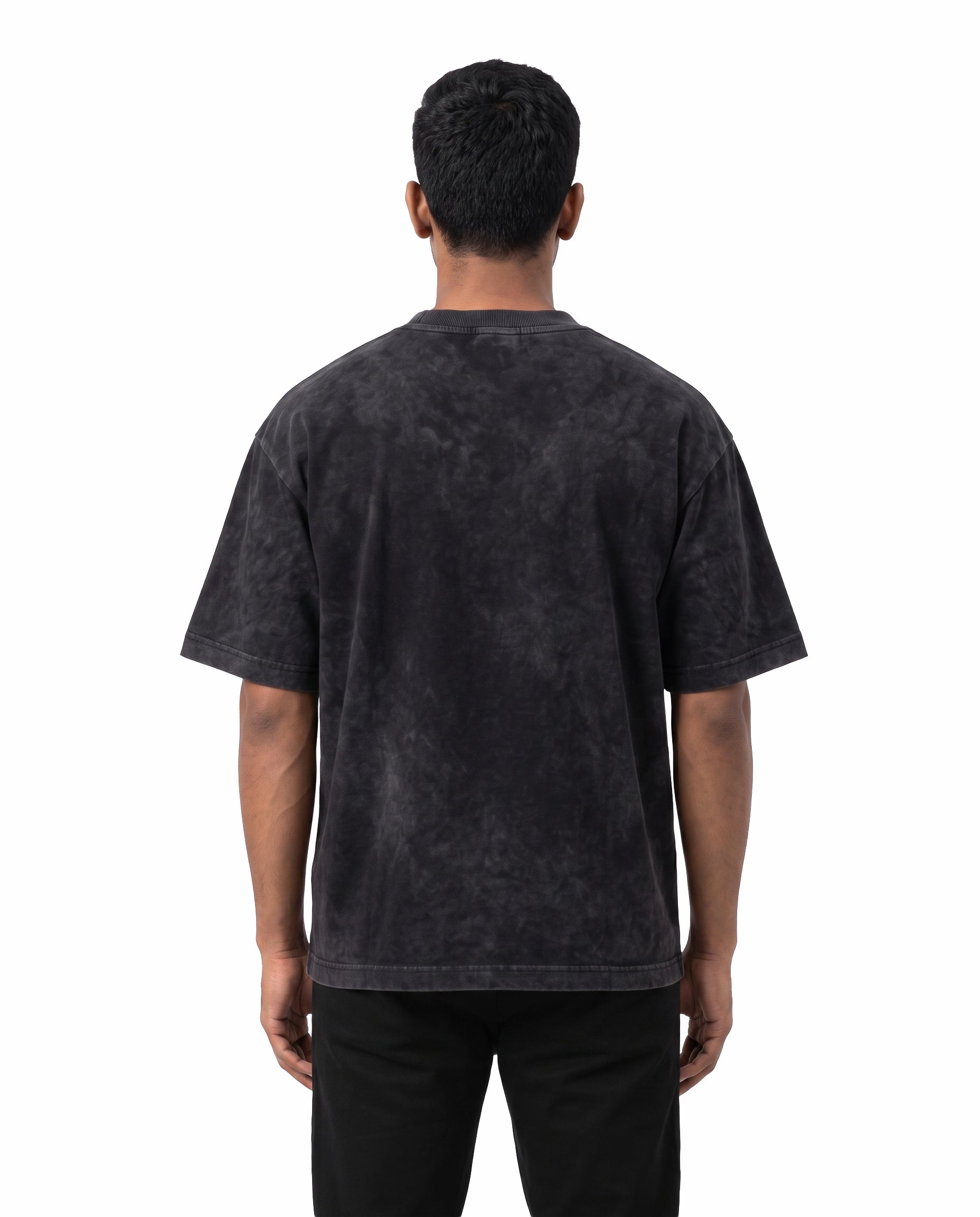 Back view of male model wearing BRO CODE unisex acid washed oversized graphic t-shirt in black in a studio setting.