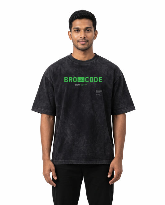 Front view of male model wearing BRO CODE unisex acid washed oversized graphic t-shirt in black in a studio setting.