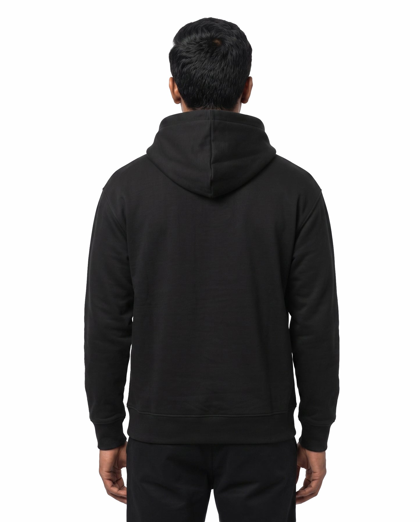 Back view of female model wearing ELLAME DESIGNLA IRUKKU - Unisex Regular Fit Hoodie in black in a studio setting.