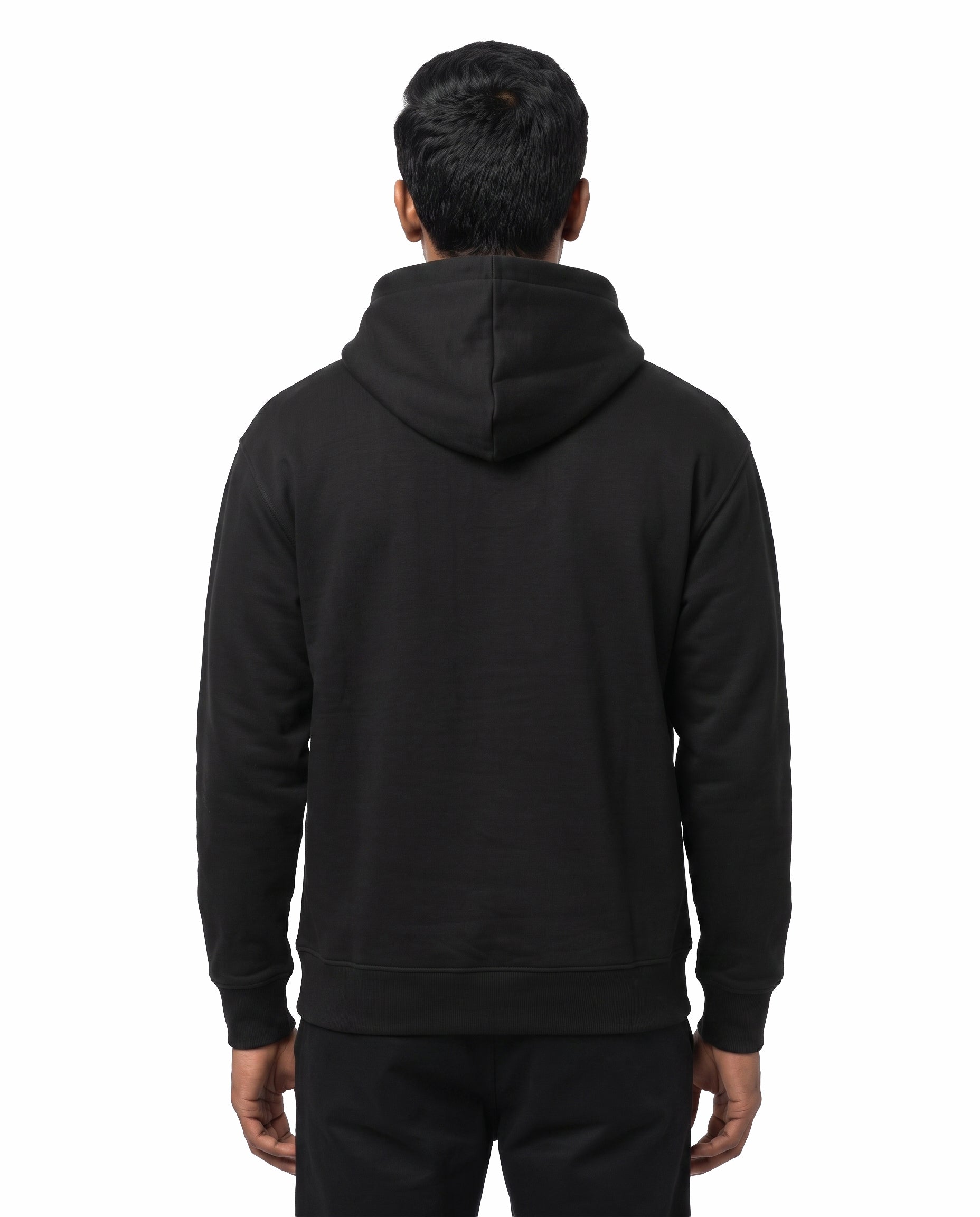 Back view of female model wearing ELLAME DESIGNLA IRUKKU - Unisex Regular Fit Hoodie in black in a studio setting.