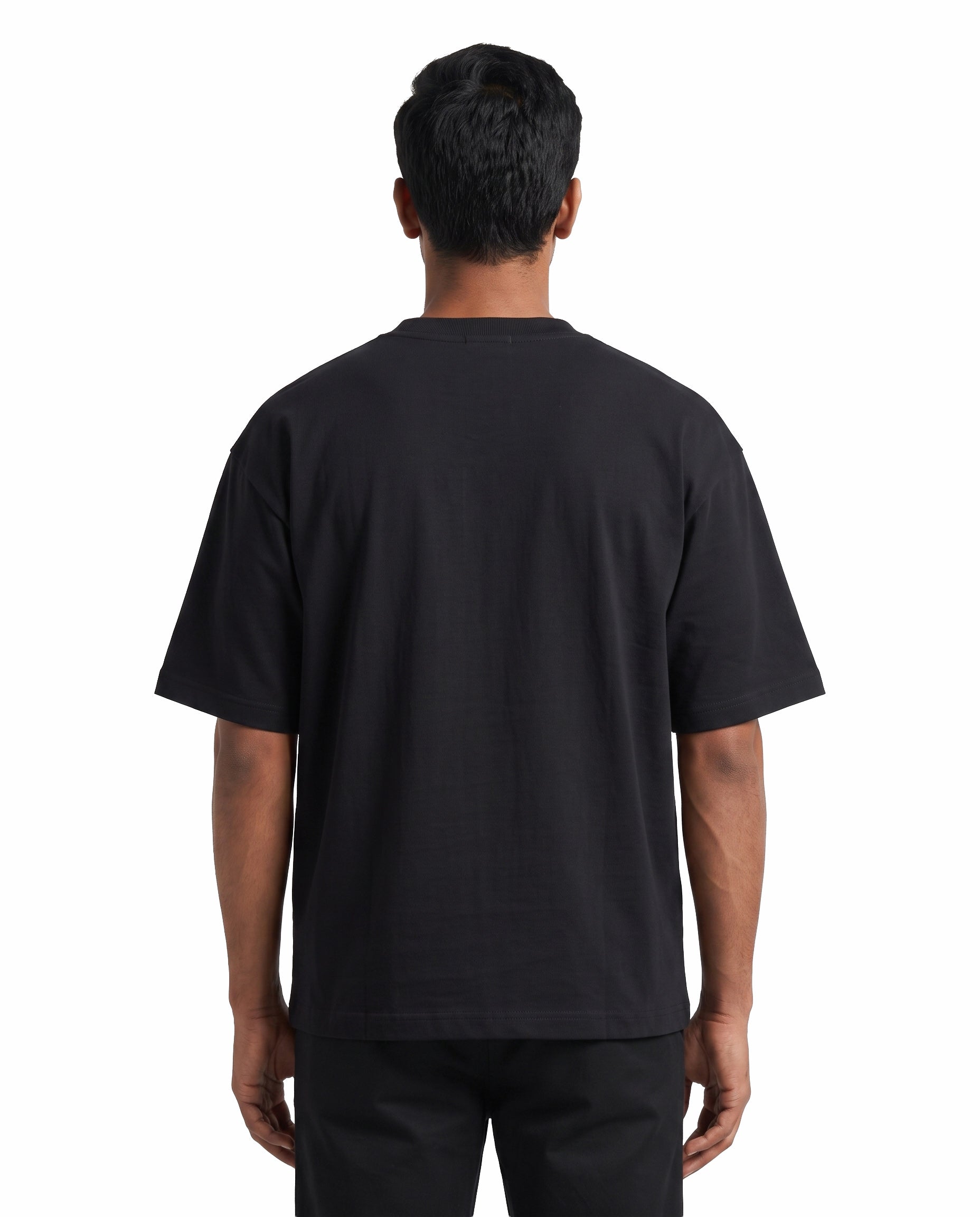 Back view of male model wearing EN FRIEND AH POLA YAARU MACHAN unisex oversized graphic t-shirt in black in a studio setting.