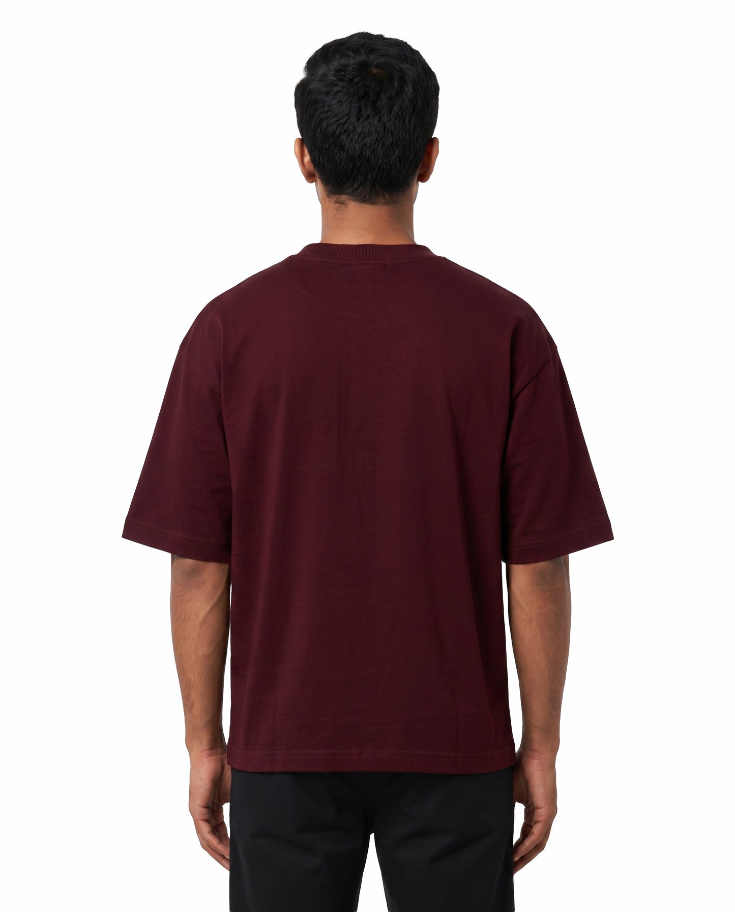 Back view of male model wearing EN FRIEND AH POLA YAARU MACHAN unisex oversized graphic t-shirt in maroon in a studio setting.