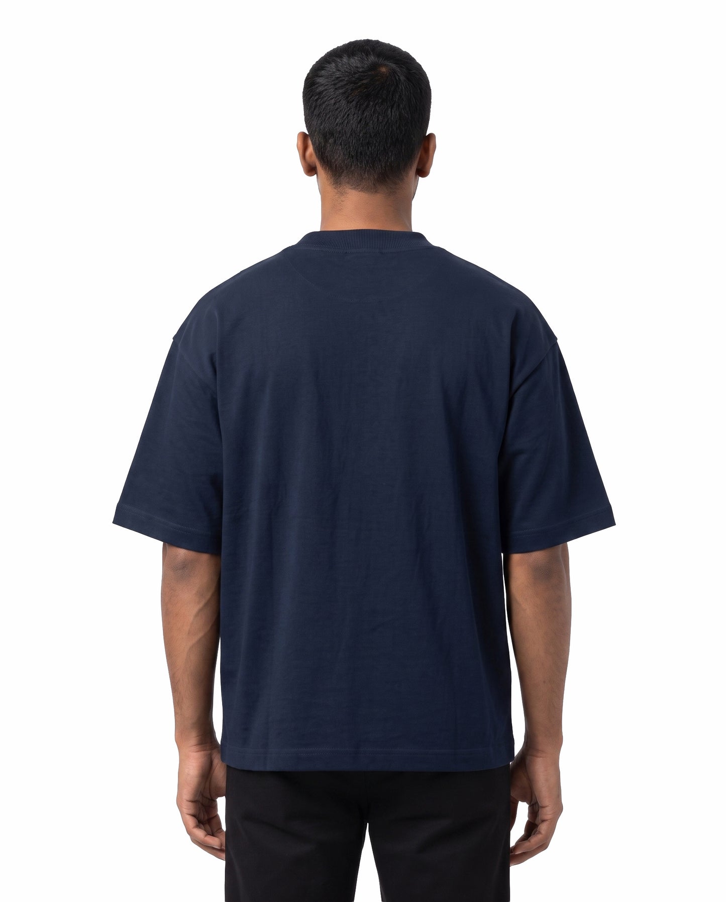 Back view of male model wearing EN FRIEND AH POLA YAARU MACHAN unisex oversized graphic t-shirt in navy blue in a studio setting.
