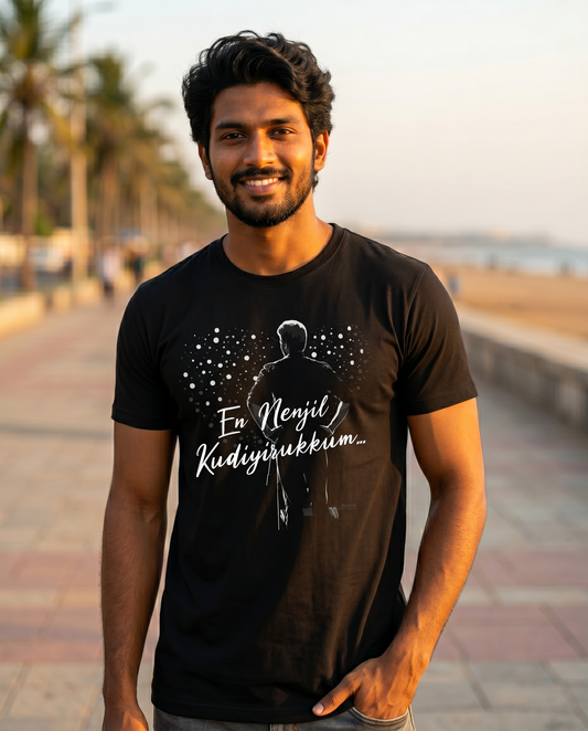 Young South Indian male wearing the EN NENJIL KUDIYIRUKKUM black men's regular-fit t-shirt in a Chennai beachside lifestyle setting.