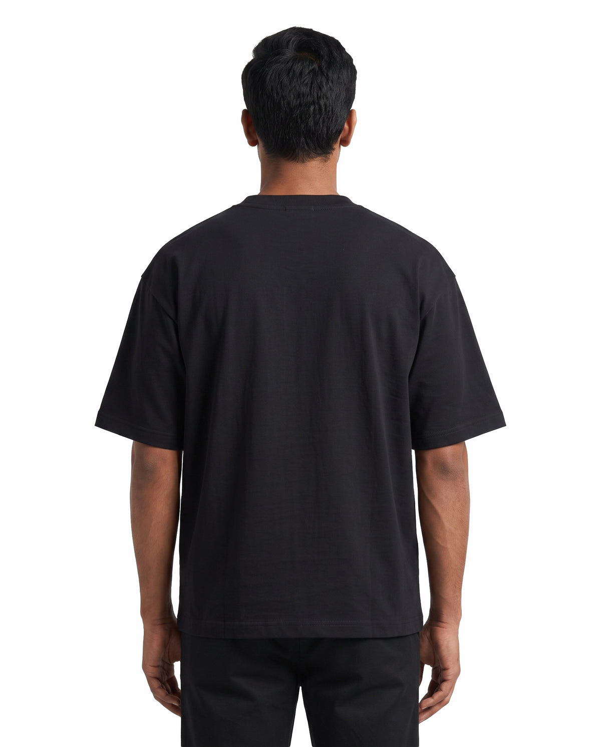 Back view of male model wearing ISAIPUYAL - Unisex Oversized Graphic T-Shirt in black in a studio setting.