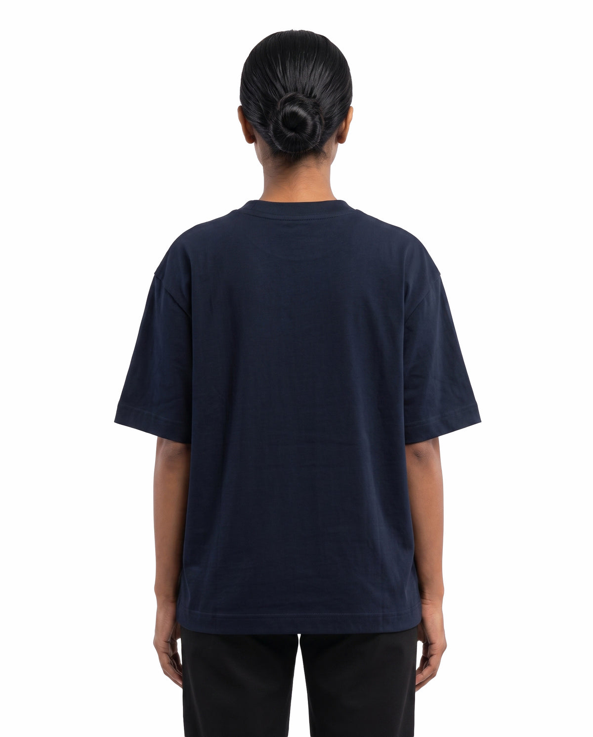 Back view of female model wearing ISAIPUYAL - Unisex Oversized Graphic T-Shirt in navy blue in a studio setting.