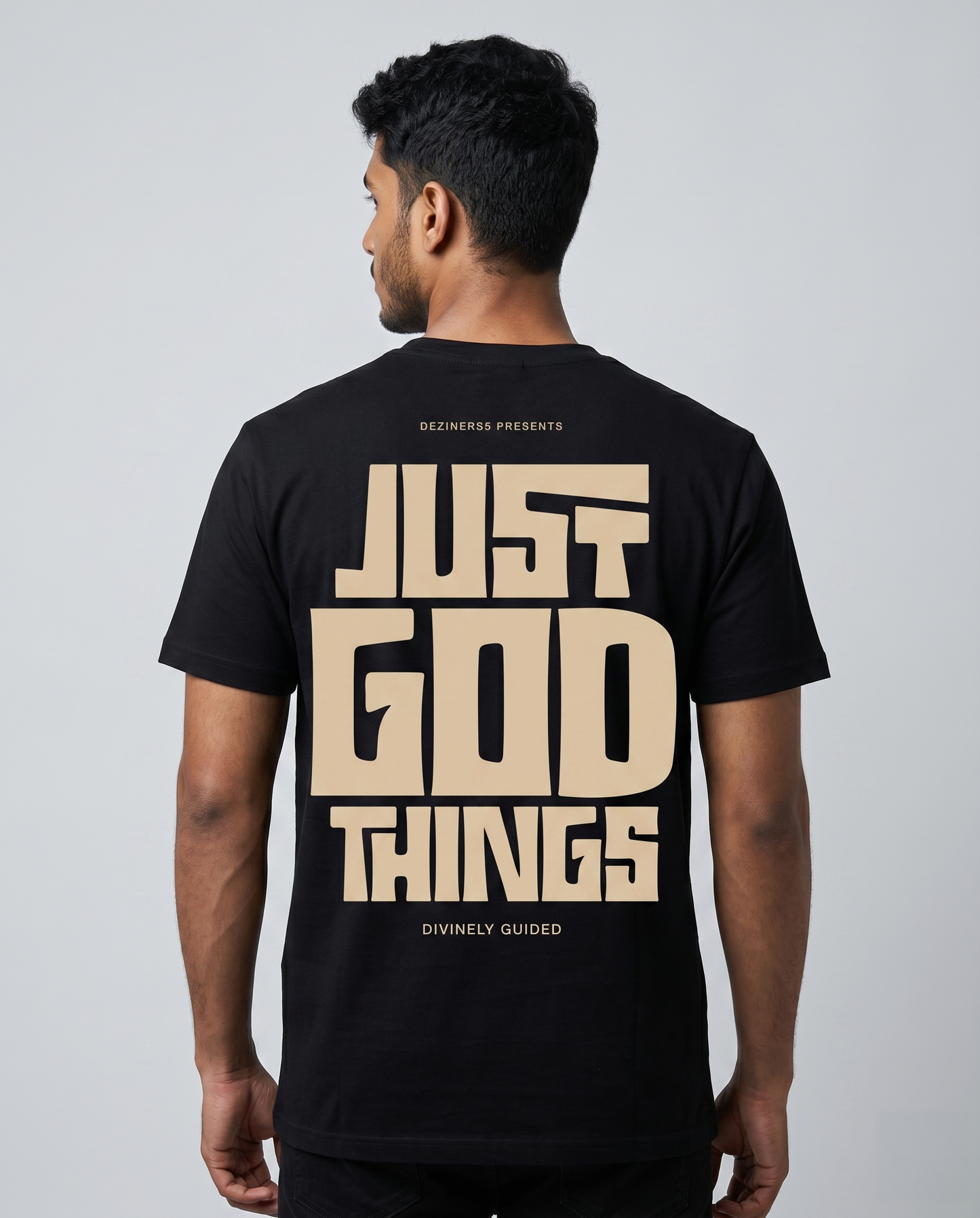 Young South Indian male model wearing JUST GOD THINGS men's regular fit black graphic t-shirt with large back graphic.