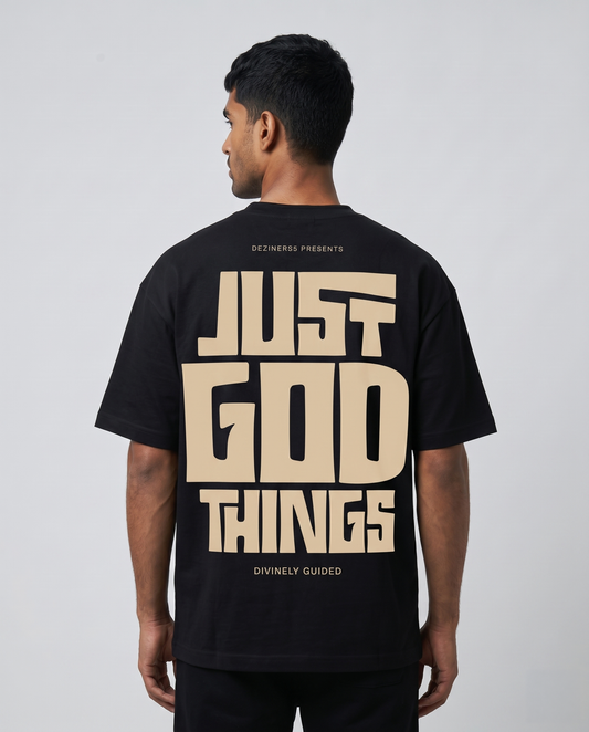 Man wearing a JUST GOD THINGS - Unisex oversized graphic t-shirt in black with text on the back, standing against a plain background.