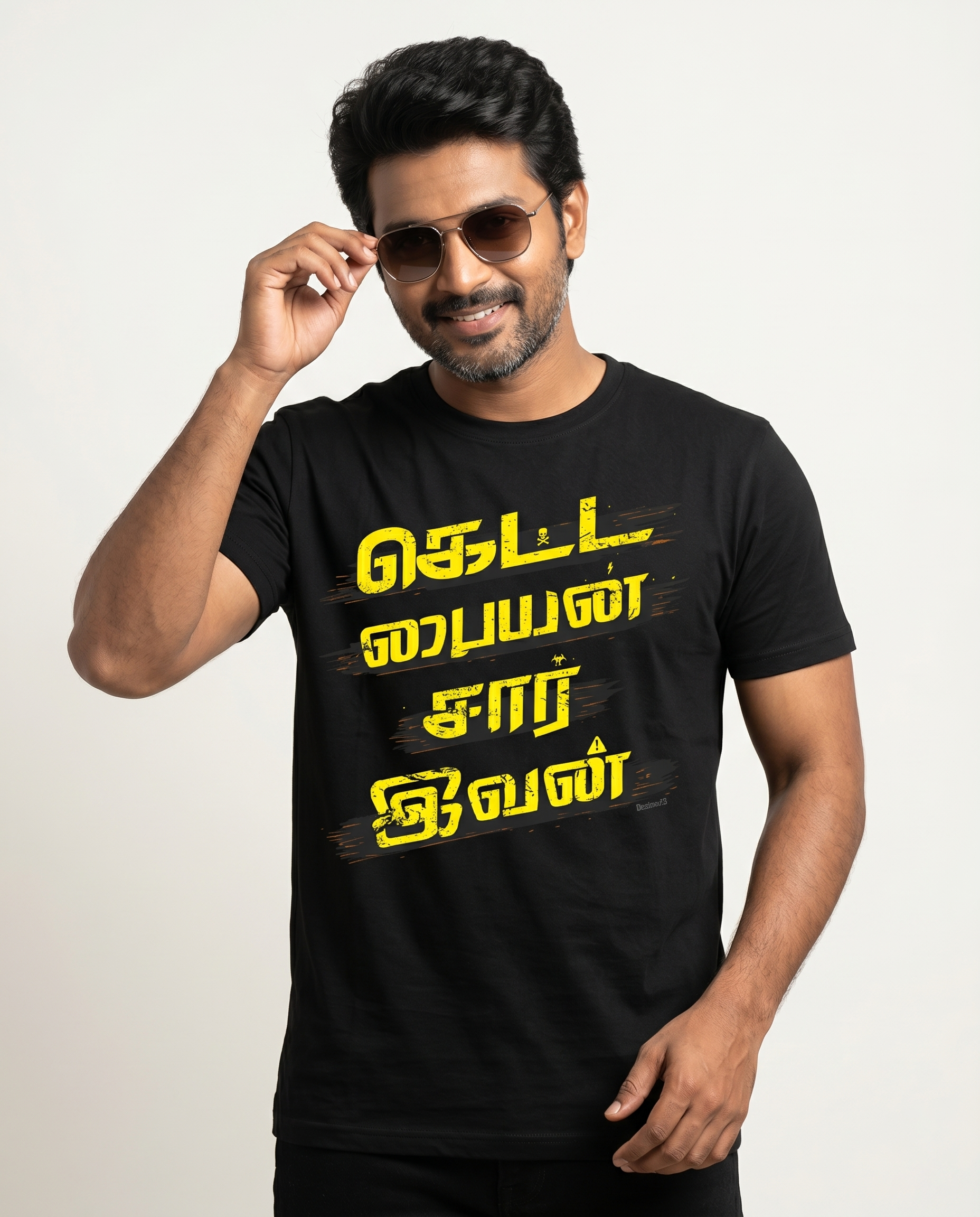 Young South Indian male wearing the KETTA PAIYAN men's regular-fit t-shirt in black in a premium studio lifestyle setting with confident superstar-inspired energy.
