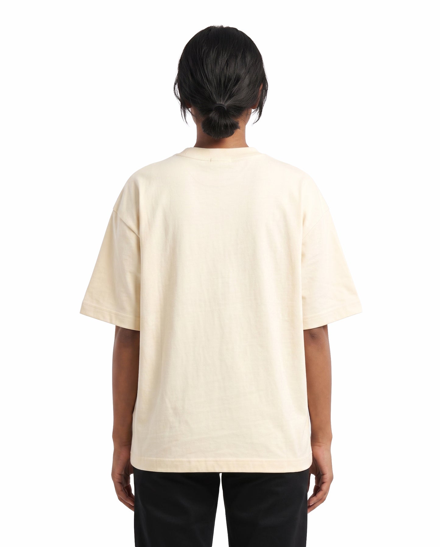 Back view of female model wearing LIFETIME VALIDITY unisex oversized graphic t-shirt in off-white in a studio setting.