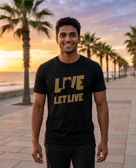 Young South Indian male wearing the LIVE & LET LIVE men's regular-fit t-shirt in black in a peaceful outdoor lifestyle setting.