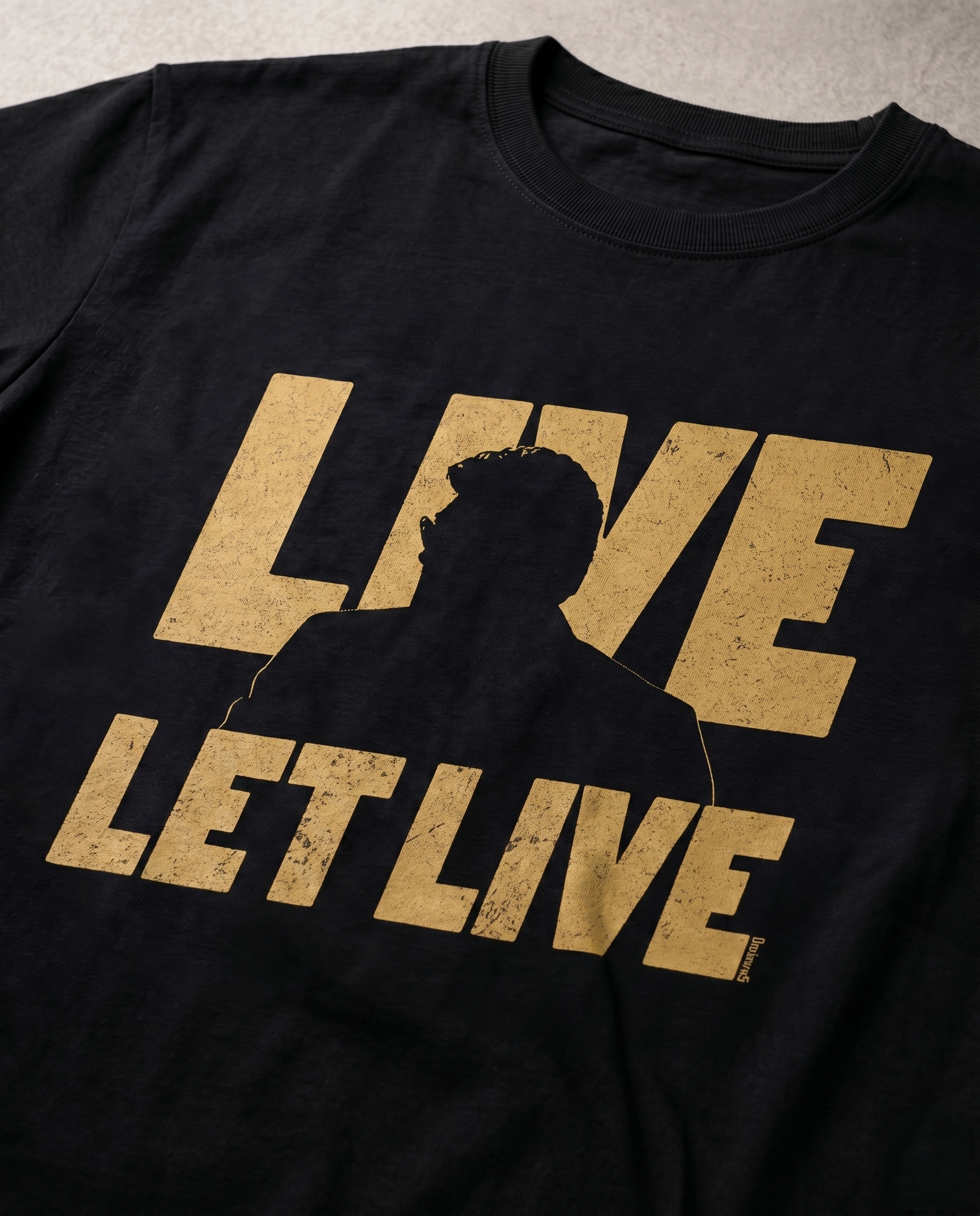 Detailed close-up of the LIVE & LET LIVE front graphic print showcasing typography and premium print quality on a black men's regular-fit t-shirt.