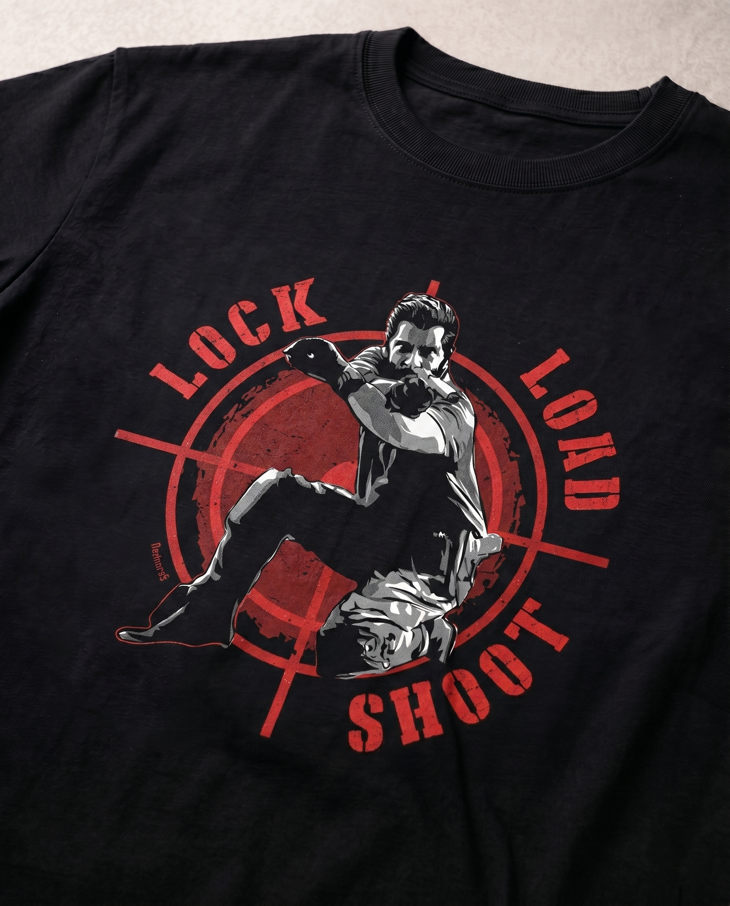 Close-up view of the LOCK LOAD SHOOT graphic print highlighting premium print quality and typography details on a black men's regular-fit t-shirt.