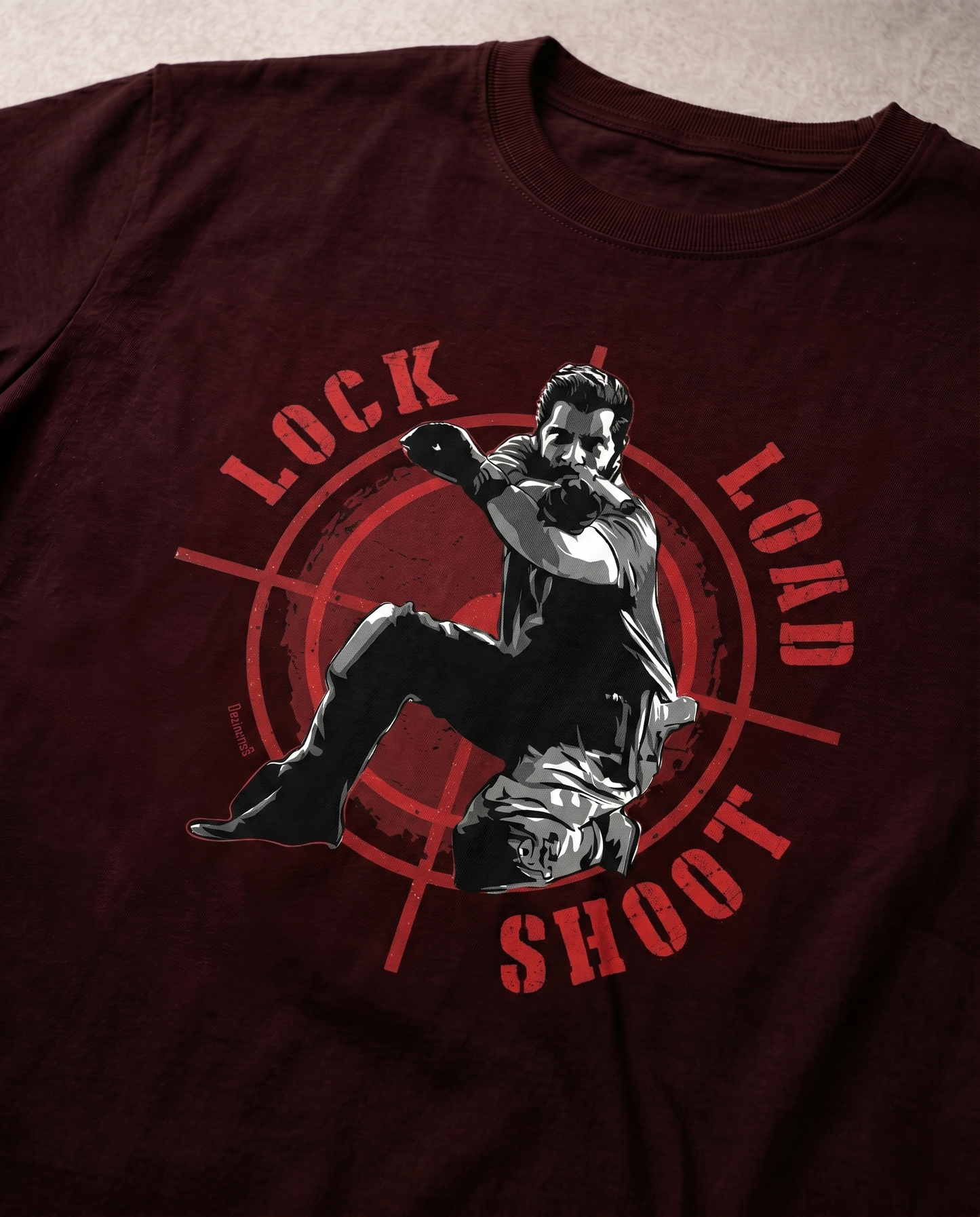Close-up view of the LOCK LOAD SHOOT graphic print highlighting premium print quality and typography details on a maroon men's regular-fit t-shirt.