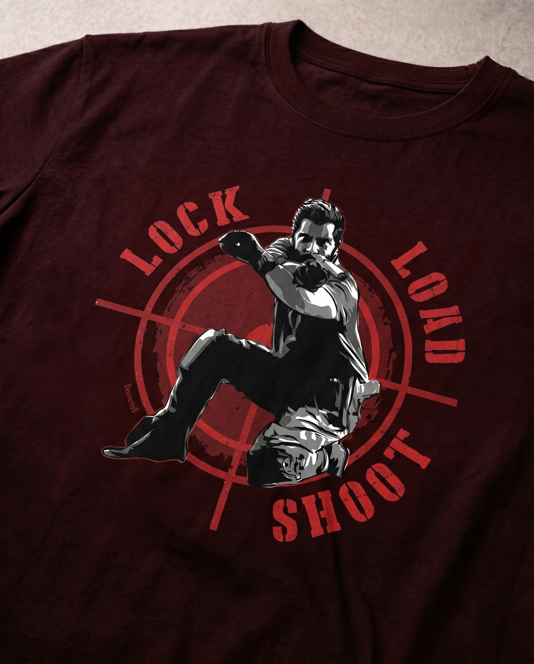 Close-up view of the LOCK LOAD SHOOT graphic print highlighting premium print quality and typography details on a maroon men's regular-fit t-shirt.