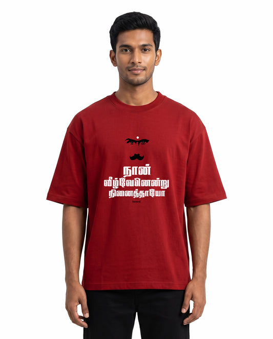 Front view of male model wearing NAAN VEEZHVENENDRU NINAITHAAIYO unisex oversized graphic t-shirt in red in a studio setting.