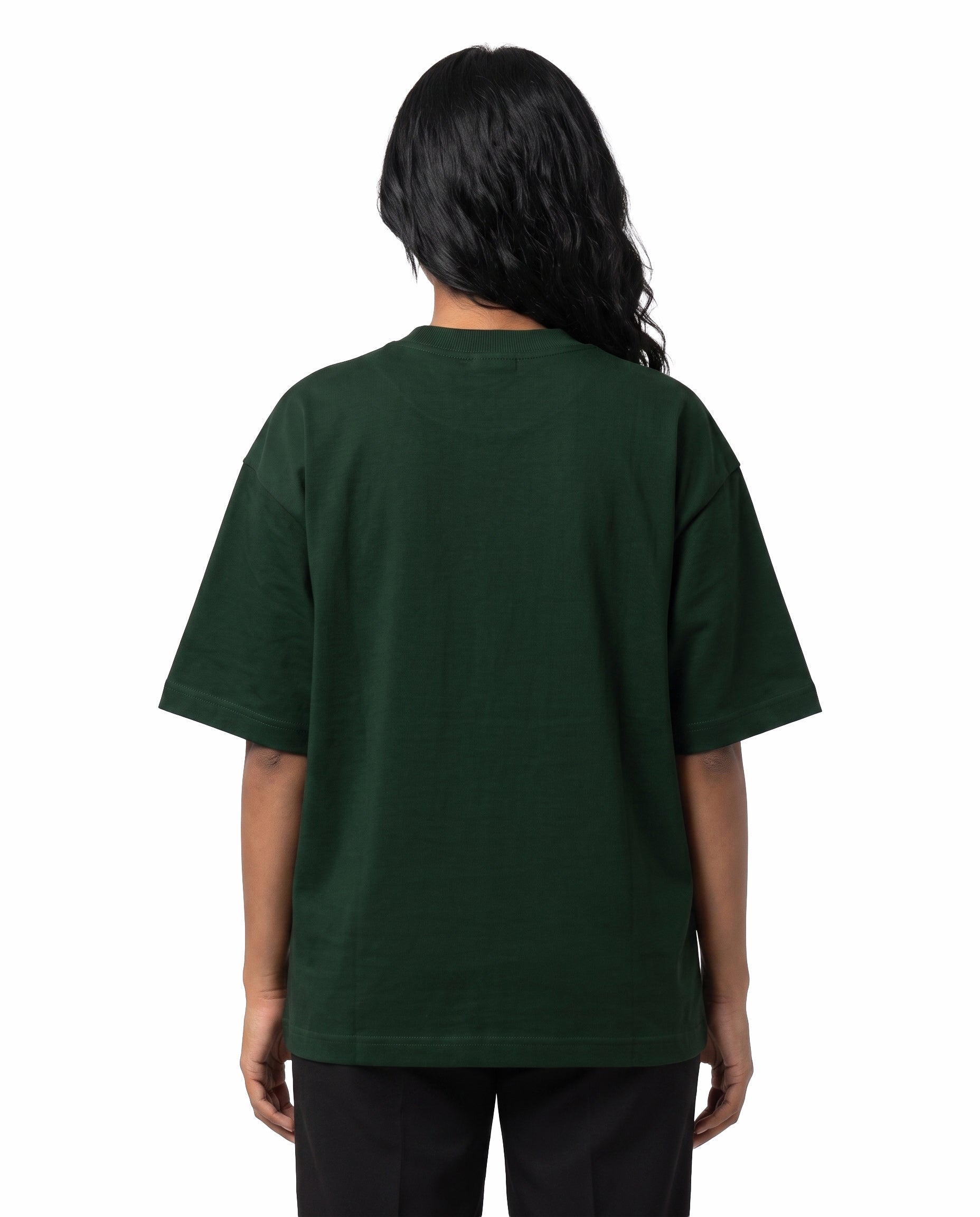 Back view of female model wearing NANBI oversized graphic t-shirt in bottle green in a studio setting.