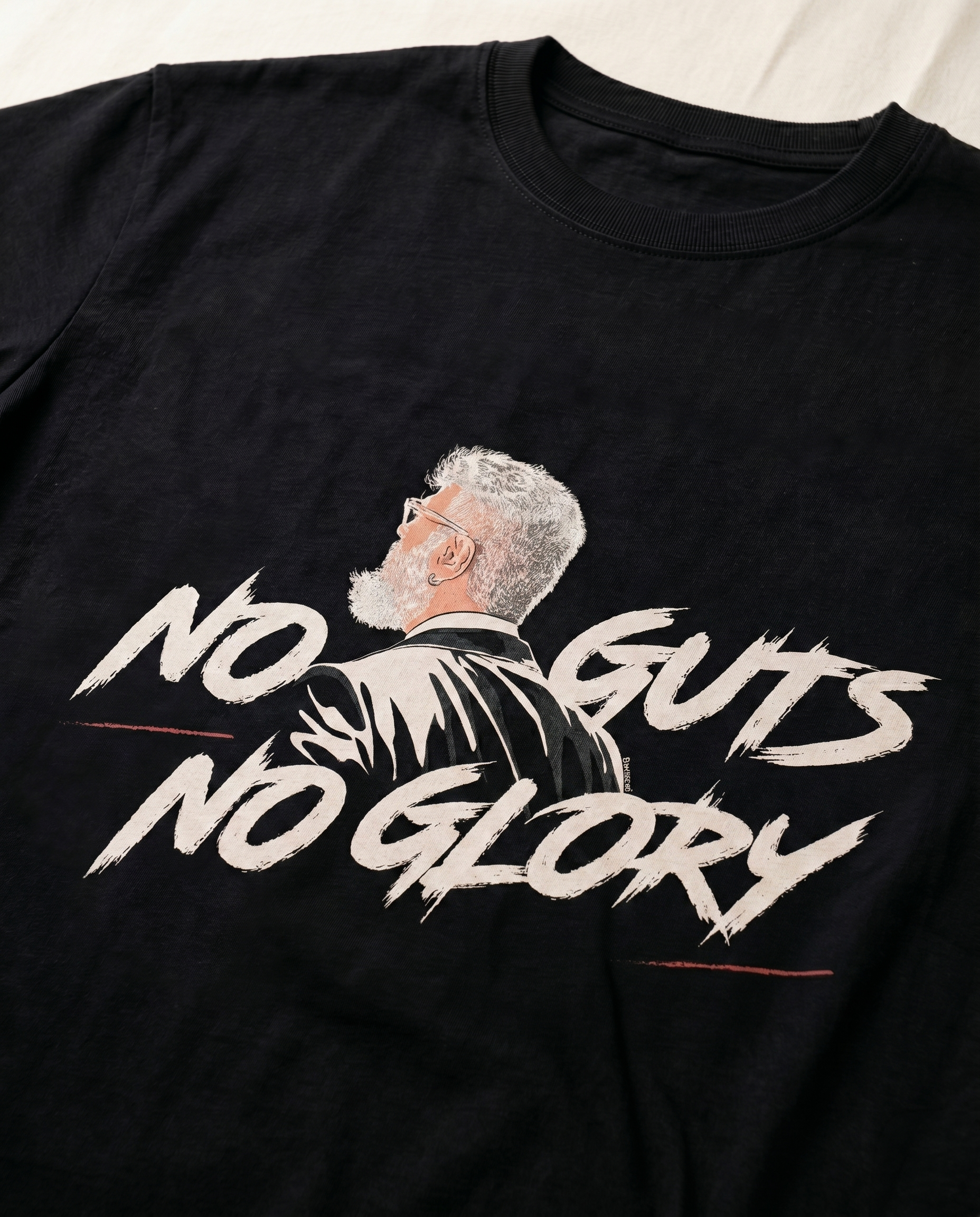 Close-up view of the NO GUTS NO GLORY front graphic print highlighting typography and premium print quality on a black men's regular-fit t-shirt.