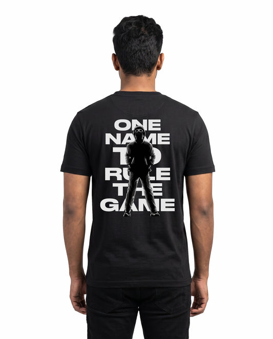 Back view of male model wearing ONE NAME men's regular-fit t-shirt in black in a studio setting.