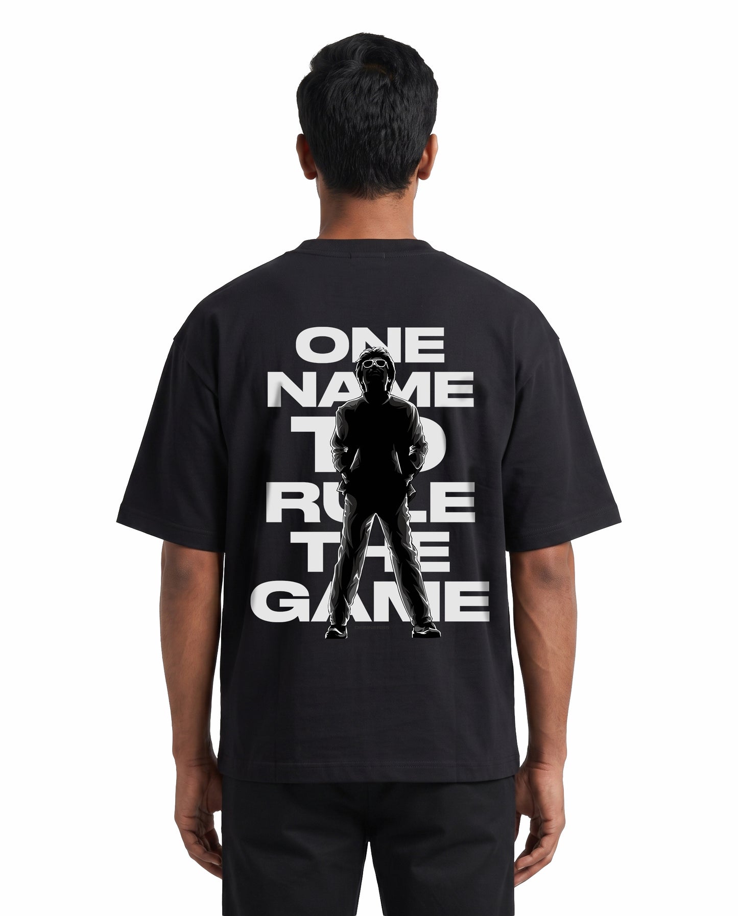 Back view of male model wearing ONE NAME unisex oversized graphic t-shirt in black in a studio setting.