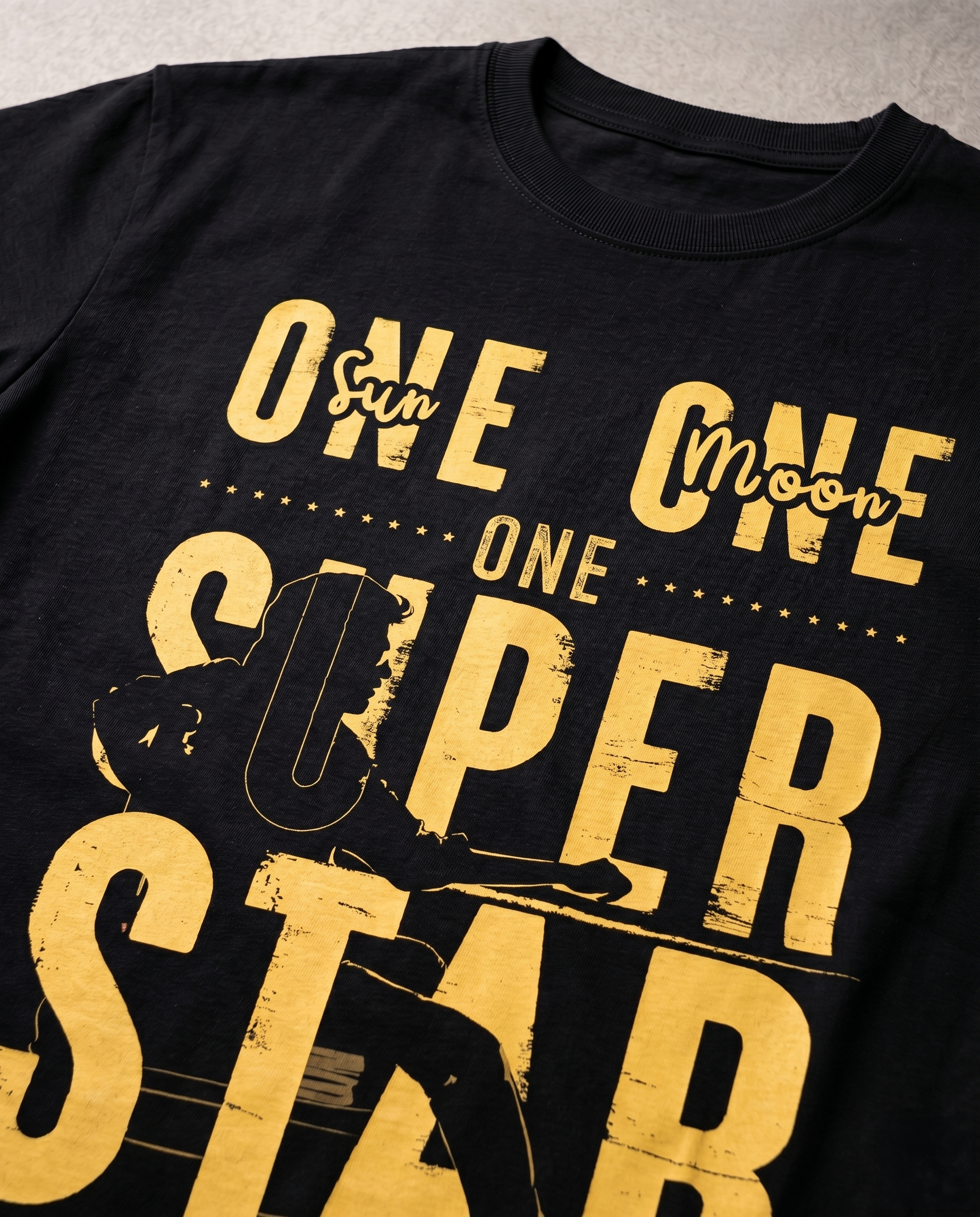Close-up print detail of ONE SUPERSTAR tribute artwork on a black regular fit t-shirt.