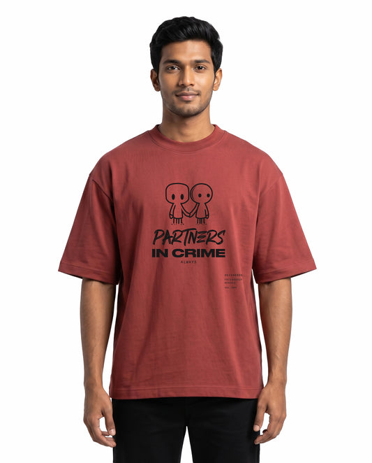 Front view of male model wearing PARTNERS IN CRIME unisex oversized graphic t-shirt in coral in a studio setting.