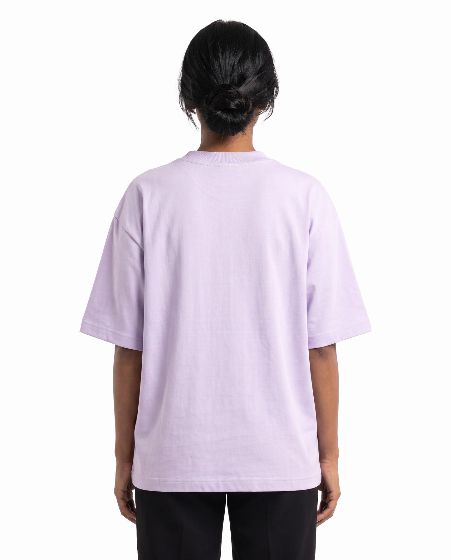 Back view of female model wearing PARTNERS IN CRIME unisex oversized graphic t-shirt in lavender in a studio setting.