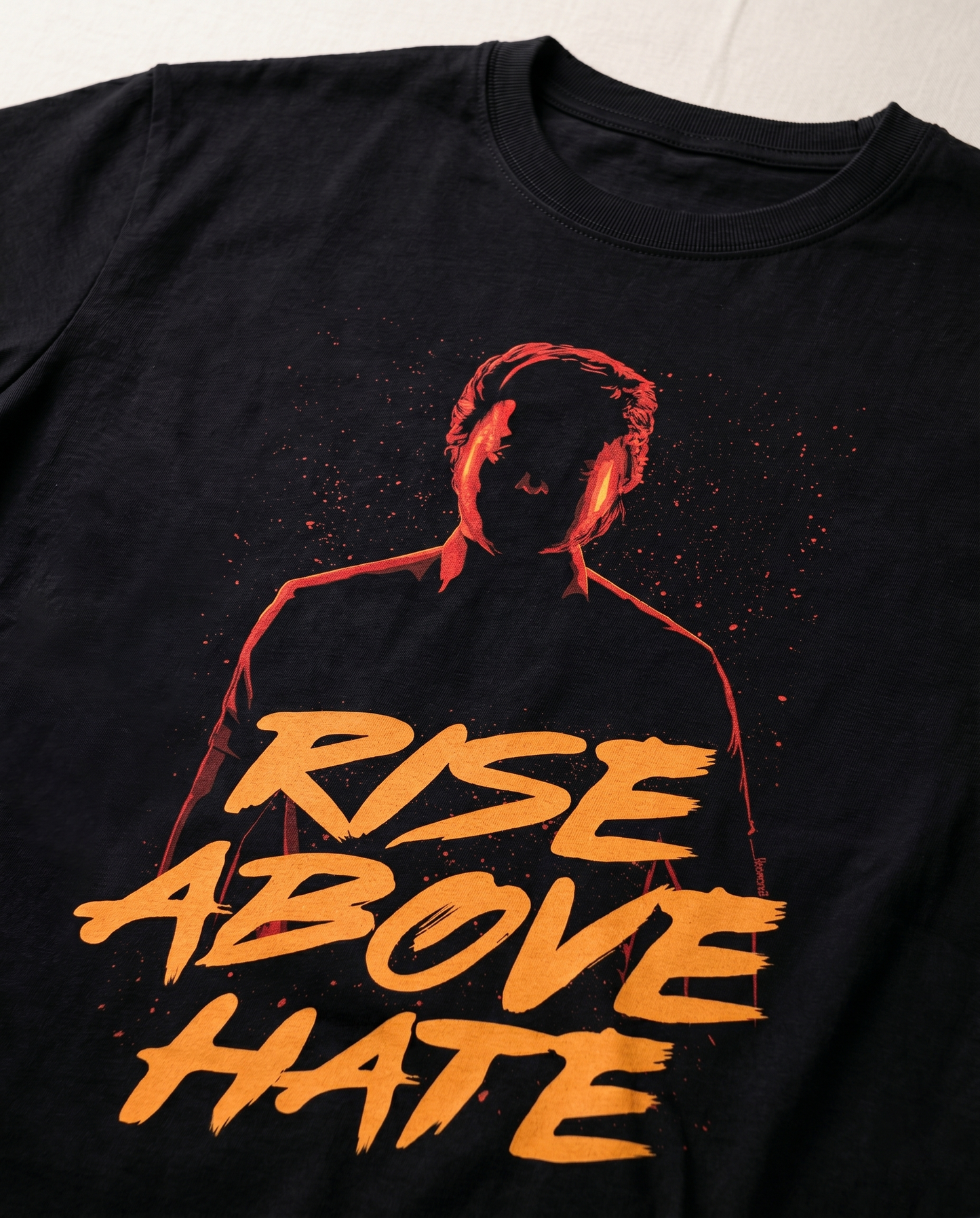 Detailed close-up of the RISE ABOVE HATE graphic print on a black men's regular-fit t-shirt.