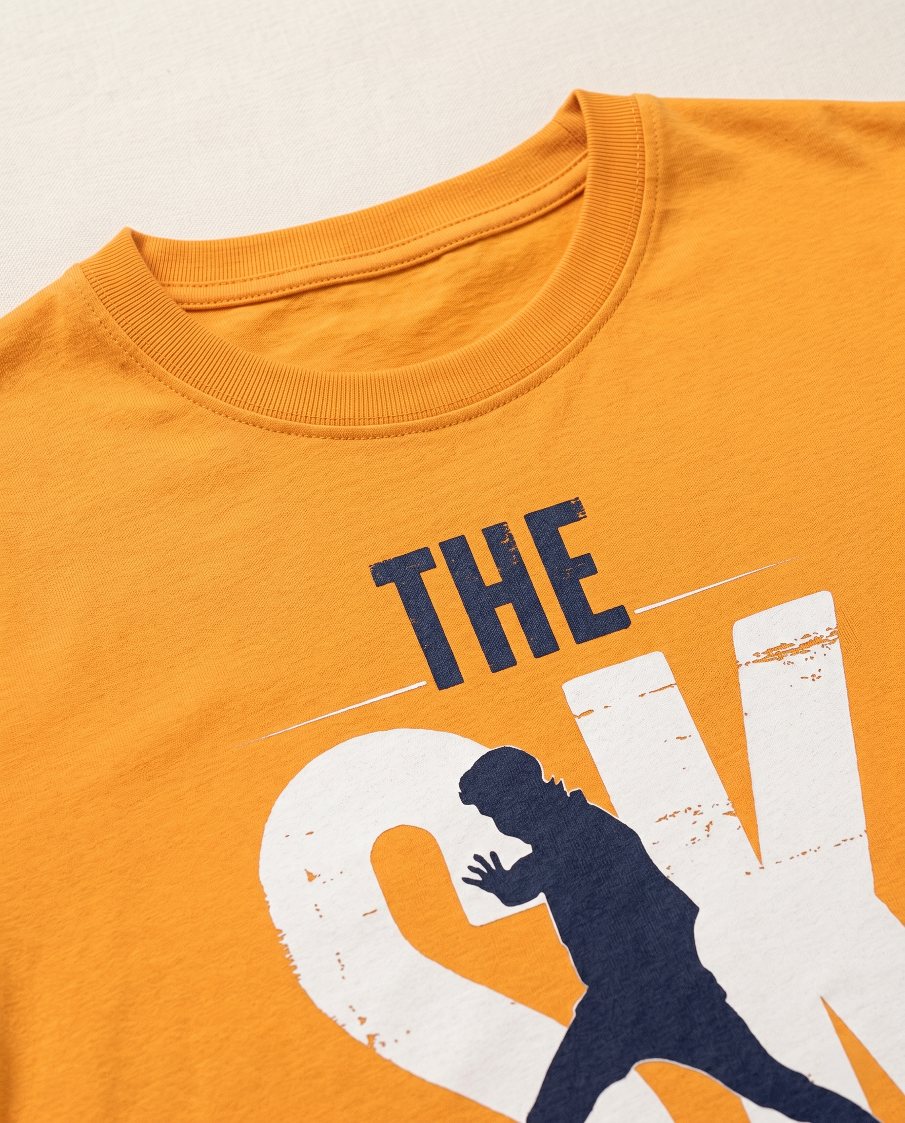 Detailed close-up of the SK FAN graphic print showcasing premium print quality and minimalist design elements on a golden yellow men's regular-fit t-shirt..