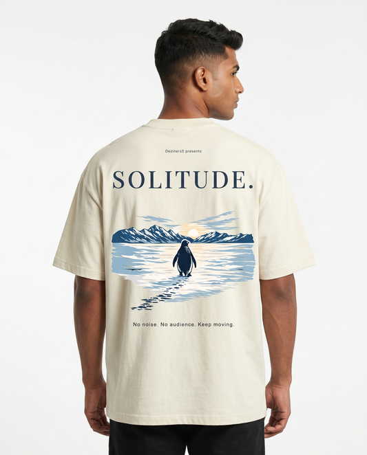 South Indian male model wearing the SOLITUDE - unisex oversized graphic t-shirt in off-white featuring large motivational penguin artwork on the back.