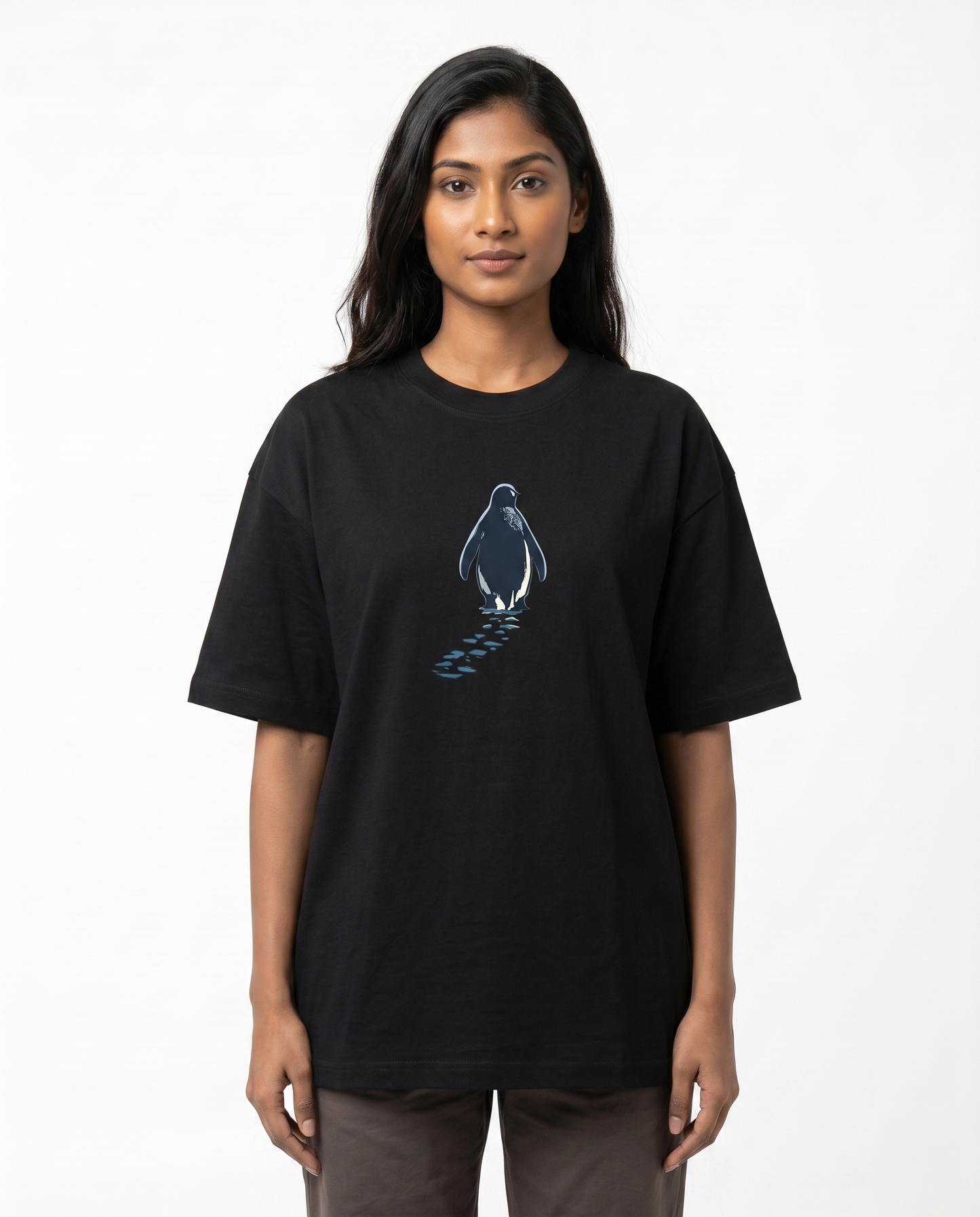 South Indian female model wearing the SOLITUDE - unisex oversized graphic t-shirt in black featuring a minimalist penguin chest graphic.