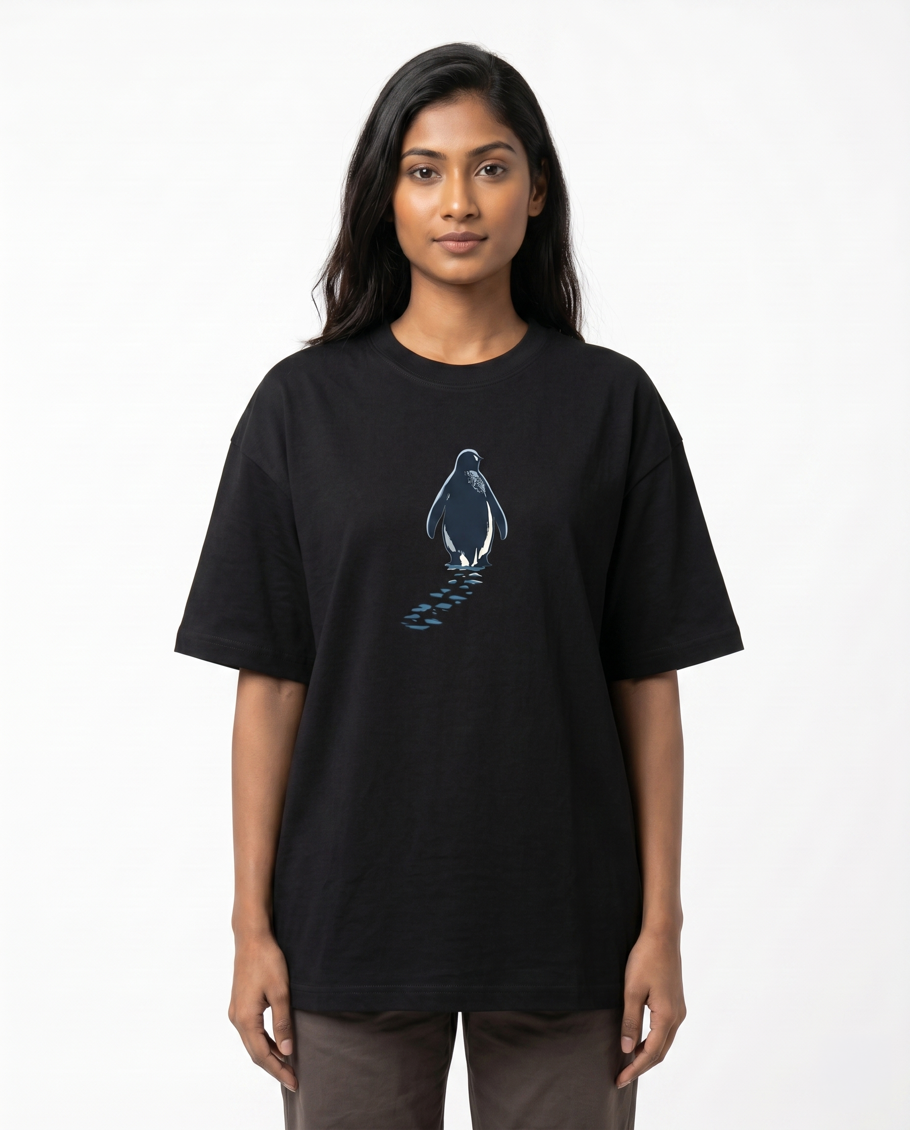 South Indian female model wearing the SOLITUDE - unisex oversized graphic t-shirt in black featuring a minimalist penguin chest graphic.