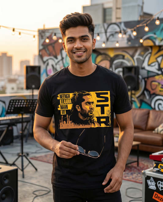 Young South Indian male wearing the STR TRIBUTE men's regular-fit t-shirt in black on a creative urban rooftop with music and youth-culture vibes.