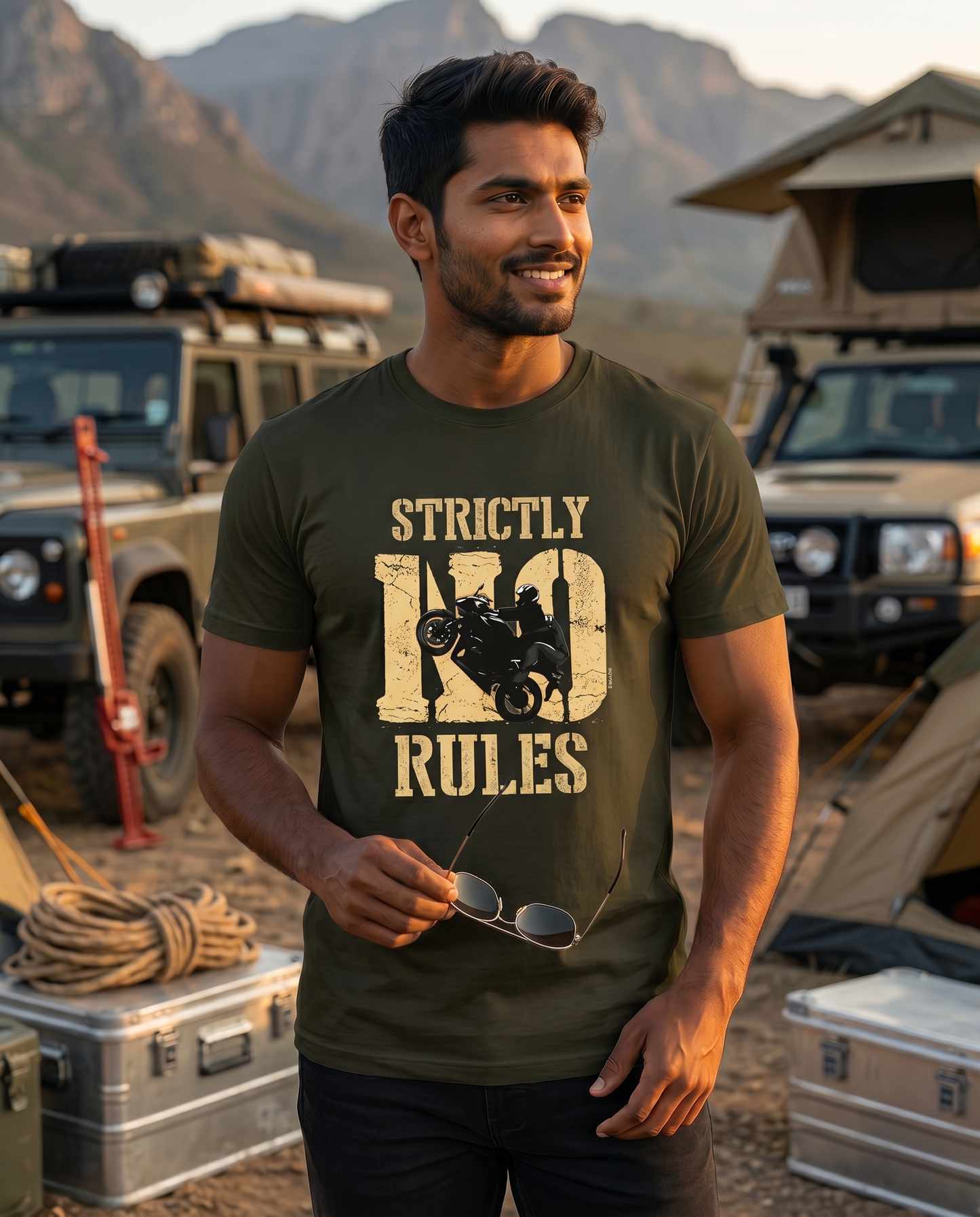 Young South Indian male wearing the STRICTLY NO RULES men's regular-fit t-shirt in olive green in an expedition base camp setting.