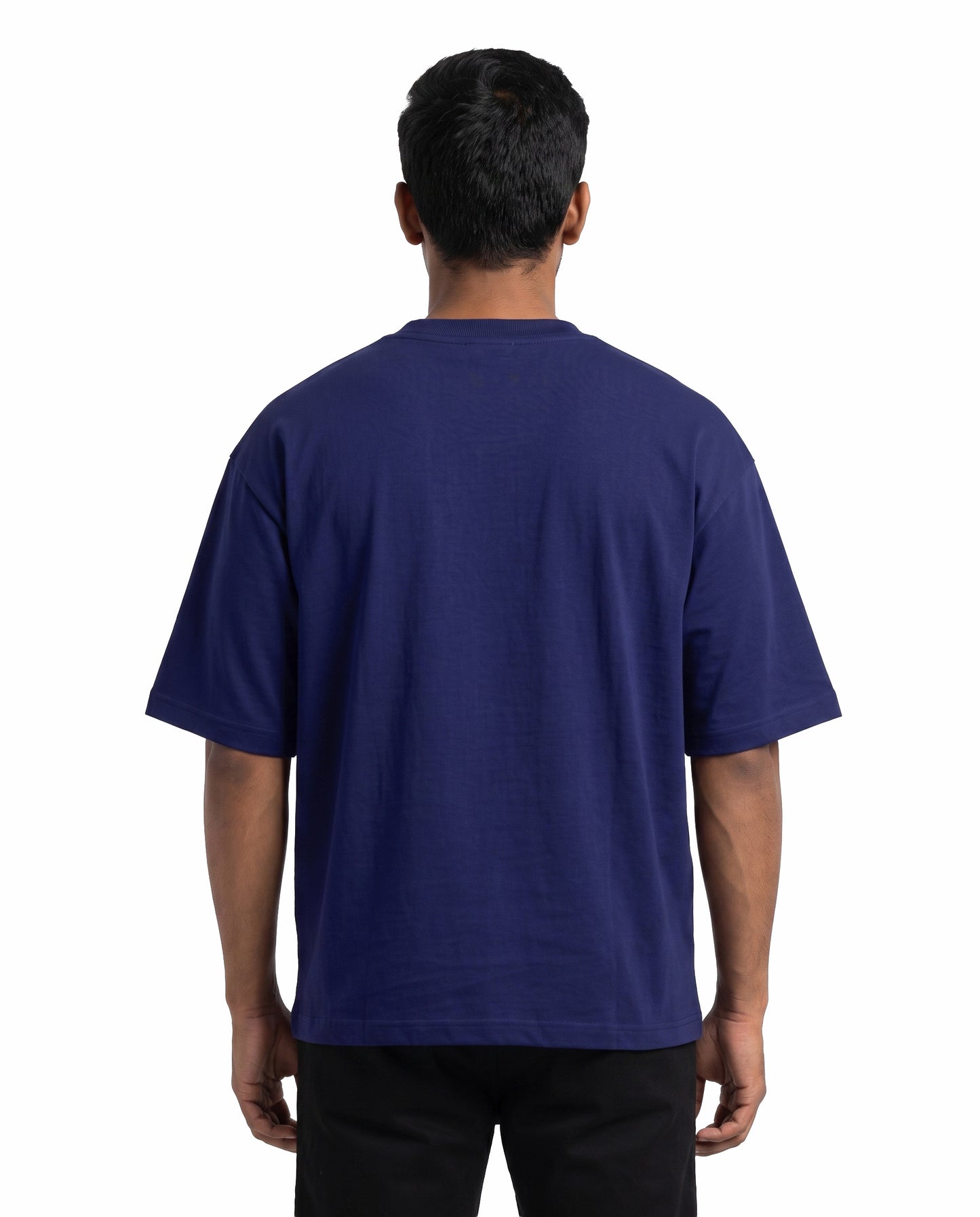Back view of male model wearing U1 VIBES unisex oversized graphic t-shirt in royal blue in a studio setting.