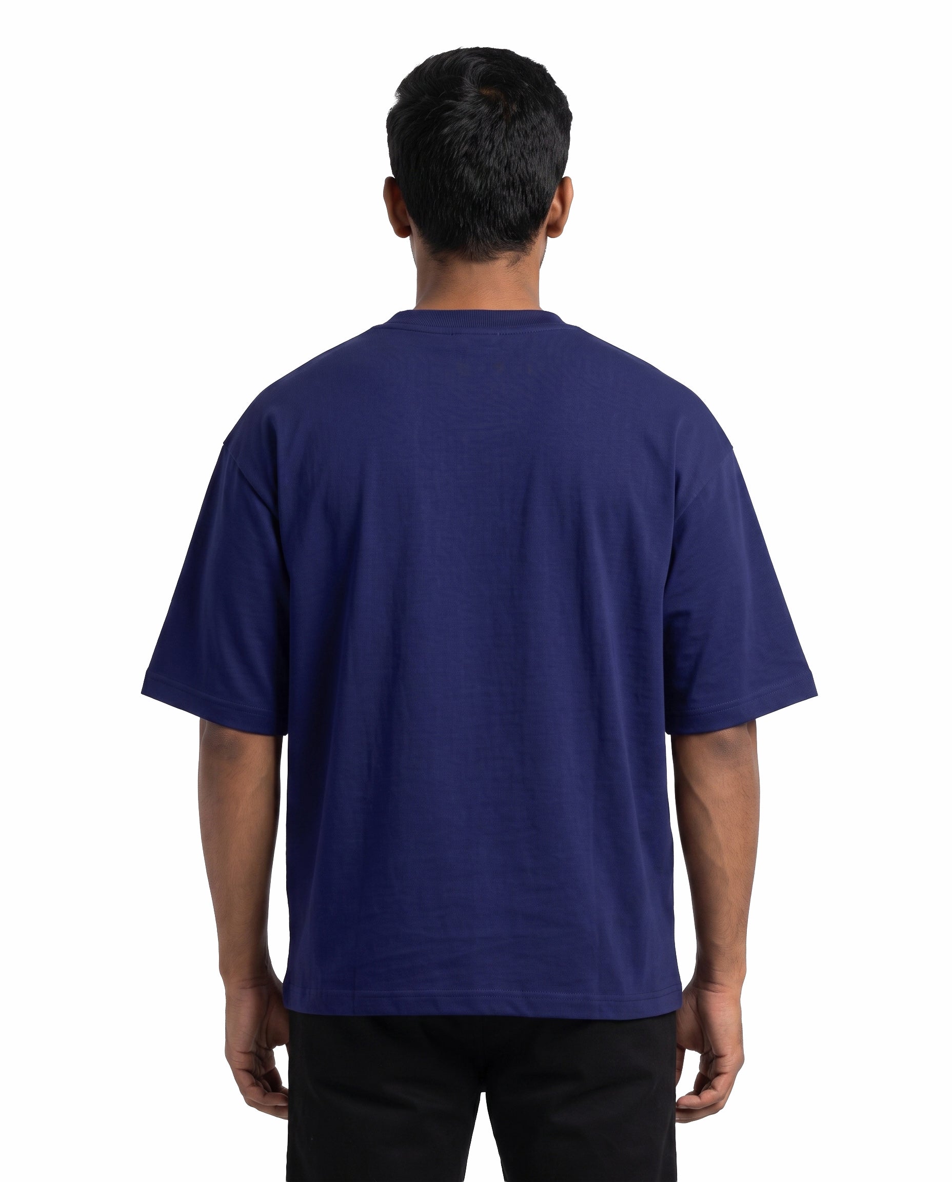 Back view of male model wearing U1 VIBES unisex oversized graphic t-shirt in royal blue in a studio setting.