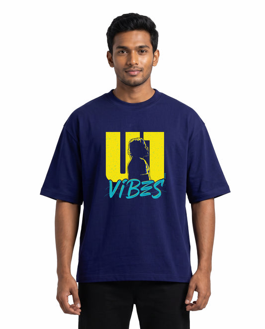 Front view of male model wearing U1 VIBES unisex oversized graphic t-shirt in royal blue in a studio setting.